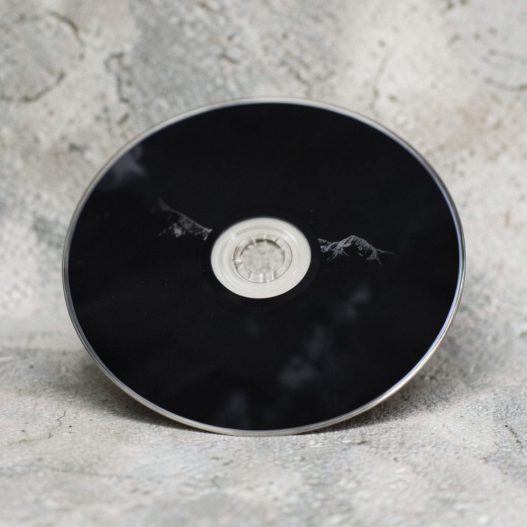 Compact disc with dark artwork sitting on a textured surface