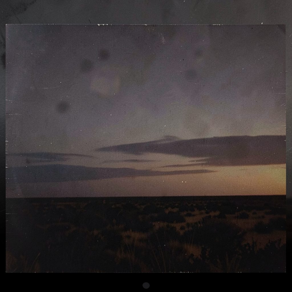 Dark textured album cover with muted earth tones and a subtle western horizon line